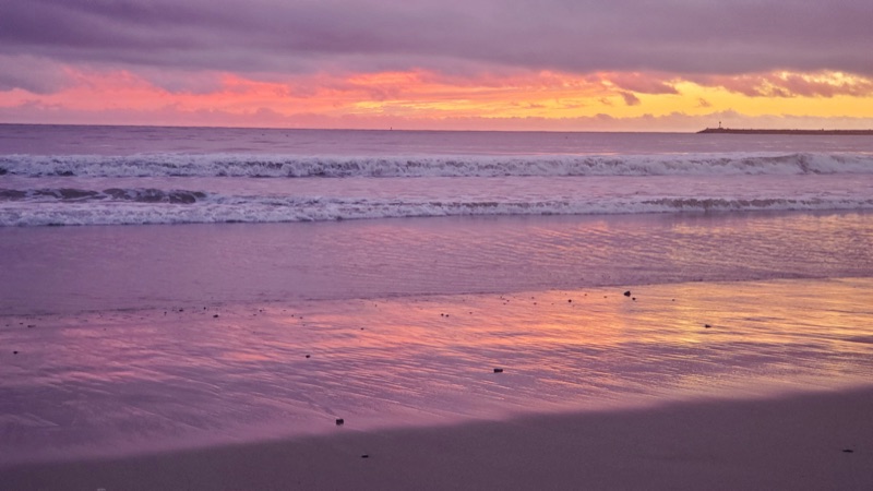 Sunset over the Pacific at Doheny State Beach, California — pink and gold sky reflecting on wet sand